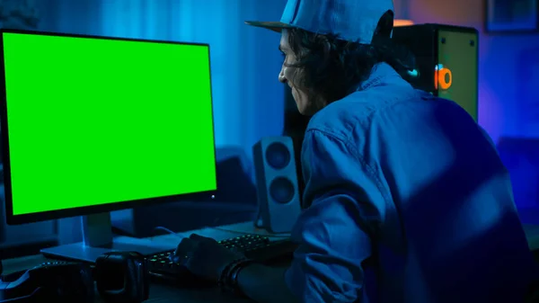 Profi vad játék online video vad-ra-a erős személyes számítógép-val színdús neon vezetett fények. Green Screen gúnyolódni. Fiatal férfi visel sapka. Nappali meleg lámpákkal. Este. — Stock Fotó