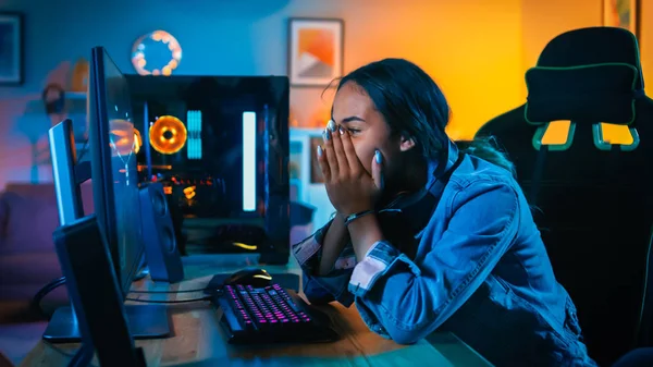 Pretty and Excited Black Gamer Girl in Headphones is Closing Her Face after Winning in First-Person Shooter Online Video Game on Her Computer. O quarto tem luzes conduzidas coloridas do néon. Noite aconchegante em casa . — Fotografia de Stock