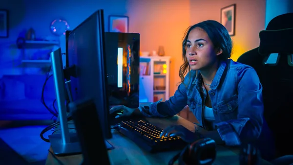 Pretty och upphetsad Black Gamer Girl har ett spänt ögonblick i sin första-person online shooter video spel på hennes dator. Rummet och datorn har färgglada Neonled-lampor. Mysig kväll hemma. — Stockfoto