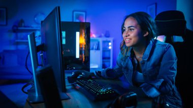 Güzel ve Heyecanlı Siyah Gamer Kız Onun Bilgisayarda First-Person Shooter Online Video Oyunu oynuyor. Oda ve Pc Mavi Neon Led Işıklar var. Evde Rahat Akşam.