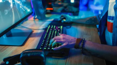 Bir Online Shooter Video Oyunu Oynarken Klavyeyi Kullanan Bir Oyuncuyu Gösteren Yakın Eller Shot. Klavye düğmeleri Yeşil Neon Işıklar vardır. Oyuncu Bilezik takıyor. Oda Karanlık.
