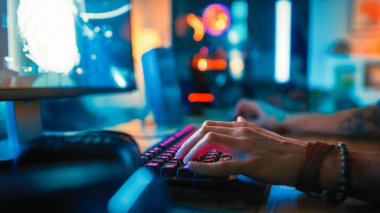 Bir Online Shooter Video Oyunu Oynarken Klavyeyi Kullanan Bir Oyuncuyu Gösteren Yakın Eller Shot. Klavye düğmeleri Pembe Neon Işıklar vardır. Oyuncu Bilezik takıyor. Oda Karanlık.