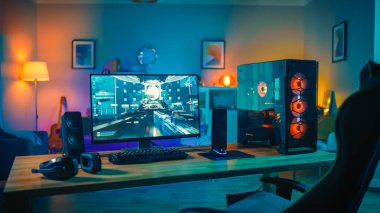 Ekranda First-Person Shooter Oyunu ile Güçlü Kişisel Bilgisayar Gamer Rig. Monitör Evde Masada Duruyor. Modern Tasarımlı Rahat Oda Sıcak ve Neon Işıkla Aydınlatıldı.