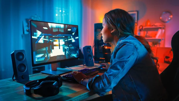 Pretty and Excited Black Gamer Girl tiene un momento tenso en su videojuego de disparos en línea en primera persona en su computadora. La habitación y la PC tienen luces led de neón coloridas. Acogedora noche en casa . — Foto de Stock