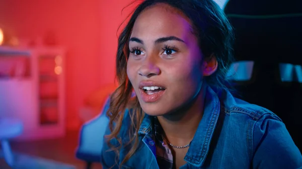 Primer plano Retrato de una hermosa joven negra emocionada viendo un video de acción en una computadora. Ella es alucinada. Screen Adds Reflections to Her Face. Acogedora habitación está iluminada con luz cálida . — Foto de Stock