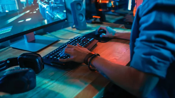 Mãos Close-Up Shot Mostrando um jogador usando o teclado enquanto joga um jogo de tiro online. Teclado tem Led luzes de néon em botões. Gamer está usando uma pulseira. O quarto é escuro . — Fotografia de Stock