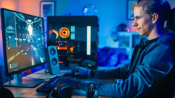 Jugador alegre que juega el juego video en línea del tirador en primera persona en su computadora personal potente. La habitación y la PC tienen luces led de neón coloridas. Acogedora noche en casa . — Foto de Stock