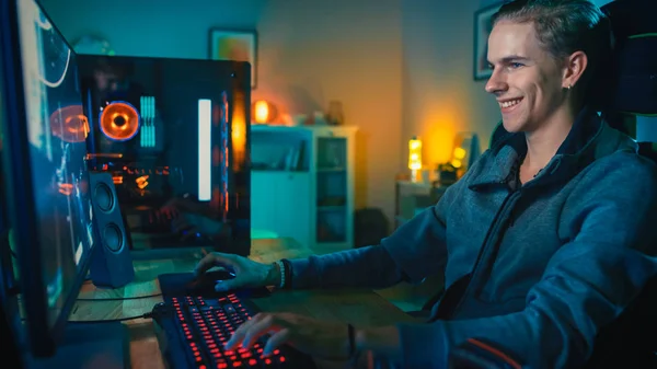 Szczęśliwy Gamer gra strzelanka z perspektywy pierwszej osoby online gry wideo na jego potężny komputer osobisty. Pokój i komputer mają kolorowe Neon LED Lights. Przytulny wieczór w domu. — Zdjęcie stockowe