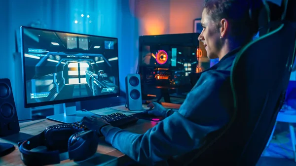 Ευτυχισμένος παίκτης παίζοντας πρώτο άτομο σε απευθείας σύνδεση βιντεοπαιχνίδι στο ισχυρό προσωπικό του υπολογιστή. Το δωμάτιο και ο υπολογιστής έχουν πολύχρωμα φώτα νέον LED. Άνετο βράδυ στο σπίτι. — Φωτογραφία Αρχείου