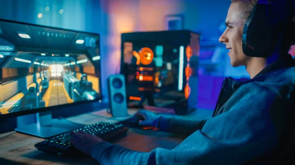 Happy gamer in de headset met een Mic Playing shooter online video game op zijn Personal computer. Kamer en PC hebben kleurrijke Neon LED-lampjes. Gezellige avond thuis. — Stockfoto