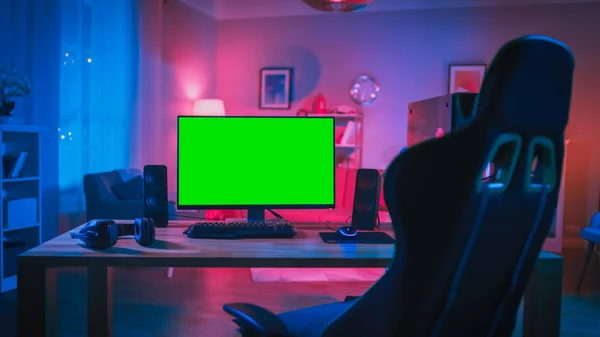 Krachtige personal computer gamer rig met mock up Green screen monitor staat op de tafel thuis. Gezellige kamer met een modern design verlicht met roze neon licht. — Stockfoto