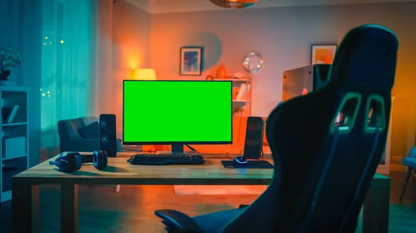 Poderoso equipamento de computador pessoal Gamer com Mock Up Green Screen Monitor fica na mesa em casa. Quarto acolhedor com design moderno é lit com luz quente e néon . — Fotografia de Stock