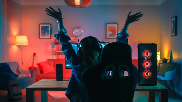 Powrót strzał Gamer Girl gry i wygranej w First-person shooter online gry wideo na jej potężny komputer osobisty. Pokój i komputer mają kolorowe Neon LED Lights. Przytulny wieczór w domu. — Zdjęcie stockowe