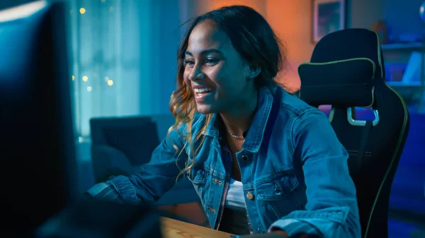 Beautiful Surprised and Excited Young Black Girl Watching Action Video on a Computer. She Has Dark Hair and Brown Eyes. Screen Adds Reflections to Her Face. Cozy Room is Lit with Warm Light. — Stock Photo, Image