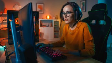 Onun Kişisel Bilgisayar da Bir Mikrofon Playing Online Video Oyunu ile Kulaklık Heyecanlı Gamer Girl. Diğer Oyuncularla Konuşuyor. Oda ve Pc Renkli Sıcak Neon Led Işıklar var. Evde Rahat Akşam.