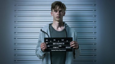 Bir Polis Karakolu'nda Uyuşturucu Bağımlısı Genç Bir Front View Mugshot için poz tutuklandı. Ağır çürükler var. Arka Plandaki Yükseklik Grafiği.