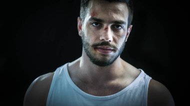 Bir Bruised Yüz Tek ayakta giyen ve agresif kameraya bakar agresif bir adam. Arka Plan Yalıtılmış Siyah.