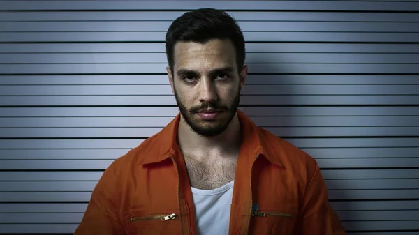 In a Police Station Arrested Man Posing for Mugshot. He's in a Prisoner Orange Jumpsuit. Height Chart in the Background. — Stock Photo, Image