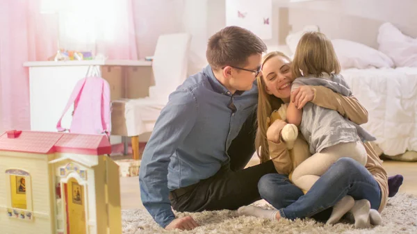 Menina bonito corre para sua mãe e pai e eles abraçá-la. Quarto das crianças é rosa, tem desenhos na parede e está cheio de brinquedos . — Fotografia de Stock