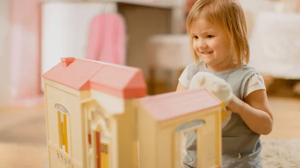 Çocuk Odasında: Sevimli Mutlu Küçük Kız Doll House ile oynamak ve bir halı üzerinde oturan. Eğlenen Çocuklu Güneşli Oturma Odası. — Stok fotoğraf