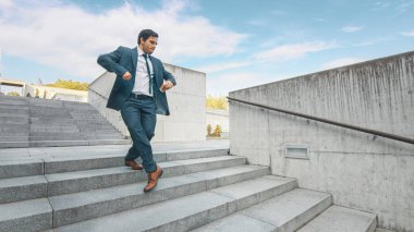 Takım Elbiseli Neşeli ve Mutlu İşadamı, Merdivenlerden Aşağı Yürürken Kahve Ve Aktif Dans Ediyor. İş Merkezi'nin Yanındaki Kentsel Beton Park'ta Sahne Çekimi. Güneşli.