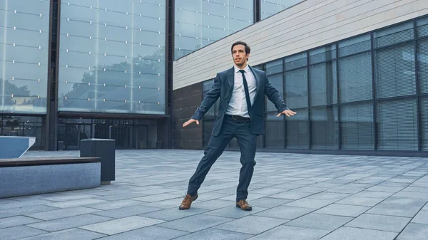 Glad och glad affärsman i en kostym är aktivt dansar på ett gatu torg. Scen skjuten i en Urban betong Park bredvid Business Center. Solig dag. — Stockfoto