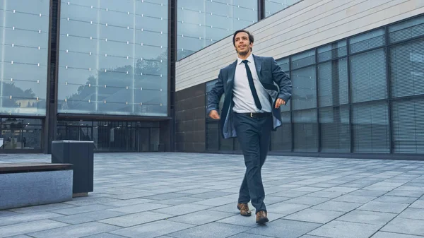 Vrolijke en gelukkige zakenman in een pak is actief dansen op een straat plein. Scène geschoten in een stedelijk betonnen park naast Business Center. Zonnige dag. — Stockfoto