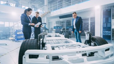 Otomotiv Tasarım Mühendisleri Elektrikli Araç Şasi Prototipi Üzerinde Çalışırken Konuşuyor. Yenilik Laboratuvarı Nda Tesis Konsept Araç Çerçevesi Tekerlekler, Süspansiyon, Motor ve Akü.