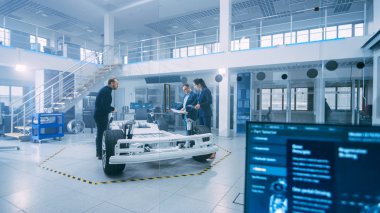 Otomotiv Tasarım Mühendisleri Elektrikli Araç Şasi Prototipi Üzerinde Çalışırken Konuşuyor. Yenilik Laboratuvarı Nda Tesis Konsept Araç Çerçevesi Tekerlekler, Süspansiyon, Motor ve Akü.