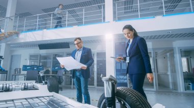 Otomotiv Tasarım Mühendisleri Elektrikli Otomobil Şasi Prototipinin Teknik Çizimlerine Bakıyor. Yenilik Laboratuvarı Nda Tesis Konsept Araç Çerçevesi Tekerlekler, Süspansiyon, Motor ve Akü.