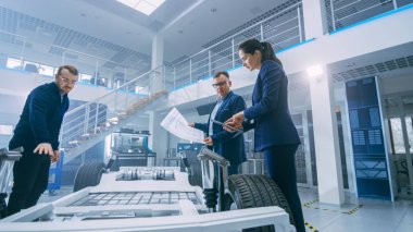 Otomotiv Tasarım Mühendisleri Elektrikli Otomobil Şasi Prototipinin Teknik Çizimlerine Bakıyor. Yenilik Laboratuvarı Nda Tesis Konsept Araç Çerçevesi Tekerlekler, Süspansiyon, Motor ve Akü.