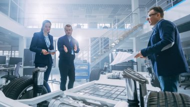 Otomotiv Tasarım Mühendisleri Elektrikli Araç Şasi Prototipi Üzerinde Çalışırken Konuşuyor. Yenilik Laboratuvarı Nda Tesis Konsept Araç Çerçevesi Tekerlekler, Süspansiyon, Motor ve Akü.