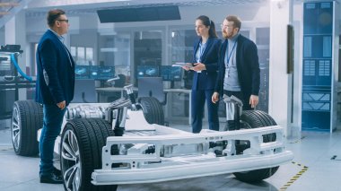 Otomotiv Tasarım Mühendisleri Elektrikli Araç Şasi Prototipi Üzerinde Çalışırken Konuşuyor. Yenilik Laboratuvarı Nda Tesis Konsept Araç Çerçevesi Tekerlekler, Süspansiyon, Motor ve Akü.