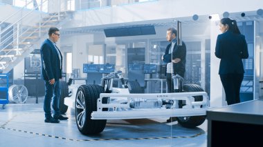 Otomotiv Tasarım Mühendisleri Elektrikli Araç Şasi Prototipi Üzerinde Çalışırken Konuşuyor. Yenilik Laboratuvarı Nda Tesis Konsept Araç Çerçevesi Tekerlekler, Süspansiyon, Motor ve Akü.