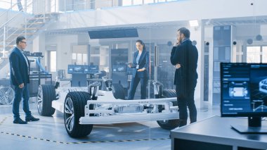 Otomotiv Tasarım Mühendisleri Elektrikli Araç Şasi Prototipi Üzerinde Çalışırken Konuşuyor. Yenilik Laboratuvarı Nda Tesis Konsept Araç Çerçevesi Tekerlekler, Süspansiyon, Motor ve Akü.