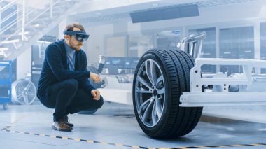 Otomotiv Mühendisi Elektrikli Otomobil Şasi Platformu üzerinde çalışıyor, Artırılmış Gerçeklik Kulaklık kullanarak. Yenilik Laboratuvarı Nda Tesis Konsept Araç Çerçevesi Tekerlekler, Süspansiyon, Motor ve Akü.