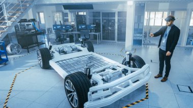 Otomotiv Mühendisi Elektrikli Otomobil Şasi Platformu üzerinde çalışıyor, Artırılmış Gerçeklik Kulaklık kullanarak. Yenilik Laboratuvarı Nda Tesis Konsept Araç Çerçevesi Tekerlekler, Süspansiyon, Motor ve Akü.