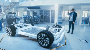 Otomotiv Mühendisi Elektrikli Otomobil Şasi Platformu üzerinde çalışıyor, Artırılmış Gerçeklik Kulaklık kullanarak. Yenilik Laboratuvarı Nda Tesis Konsept Araç Çerçevesi Tekerlekler, Süspansiyon, Motor ve Akü.