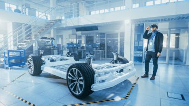 Otomotiv Mühendisi Elektrikli Otomobil Şasi Platformu üzerinde çalışıyor, Artırılmış Gerçeklik Kulaklık kullanarak. Yenilik Laboratuvarı Nda Tesis Konsept Araç Çerçevesi Tekerlekler, Süspansiyon, Motor ve Akü.