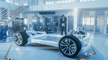 Otomotiv Mühendisi Elektrikli Otomobil Şasi Platformu üzerinde çalışıyor, Artırılmış Gerçeklik Kulaklık kullanarak. Yenilik Laboratuvarı Nda Tesis Konsept Araç Çerçevesi Tekerlekler, Süspansiyon, Motor ve Akü.