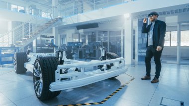 Otomotiv Mühendisi Elektrikli Otomobil Şasi Platformu üzerinde çalışıyor, Artırılmış Gerçeklik Kulaklık kullanarak. Yenilik Laboratuvarı Nda Tesis Konsept Araç Çerçevesi Tekerlekler, Süspansiyon, Motor ve Akü.