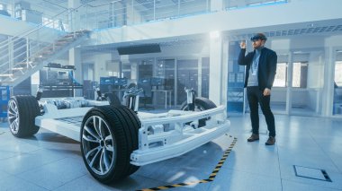 Otomotiv Mühendisi Elektrikli Otomobil Şasi Platformu üzerinde çalışıyor, Artırılmış Gerçeklik Kulaklık kullanarak. Yenilik Laboratuvarı Nda Tesis Konsept Araç Çerçevesi Tekerlekler, Süspansiyon, Motor ve Akü.