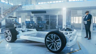 Otomotiv Mühendisi Elektrikli Otomobil Şasi Platformu üzerinde çalışıyor, Artırılmış Gerçeklik Kulaklık kullanarak. Yenilik Laboratuvarı Nda Tesis Konsept Araç Çerçevesi Tekerlekler, Süspansiyon, Motor ve Akü.