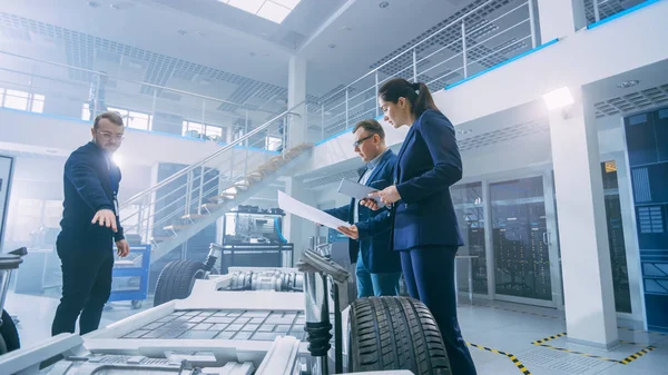 Team of Automobile Design Engineers in Automotive Innovation Facility. Eles estão trabalhando no protótipo de chassi de plataforma de carro elétrico que inclui rodas, suspensão, motor híbrido e bateria . — Fotografia de Stock