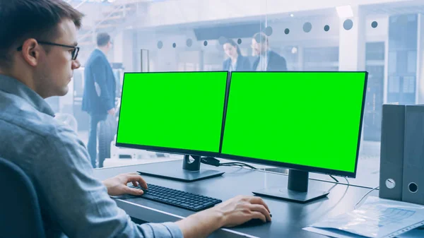 전문 엔지니어는 녹색 화면 모형 템플릿이있는 컴퓨터에서 작동합니다. 하이테크 개발 실험실에 서 있는 배터리와 엔진을 갖춘 전기 자동차 섀시 프로토타입. — 스톡 사진