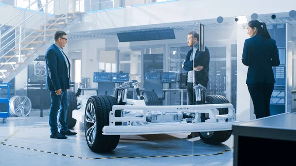 Otomotiv Tasarım Mühendisleri Elektrikli Araç Şasi Prototipi Üzerinde Çalışırken Konuşuyor. Yenilik Laboratuvarı Nda Tesis Konsept Araç Çerçevesi Tekerlekler, Süspansiyon, Motor ve Akü.