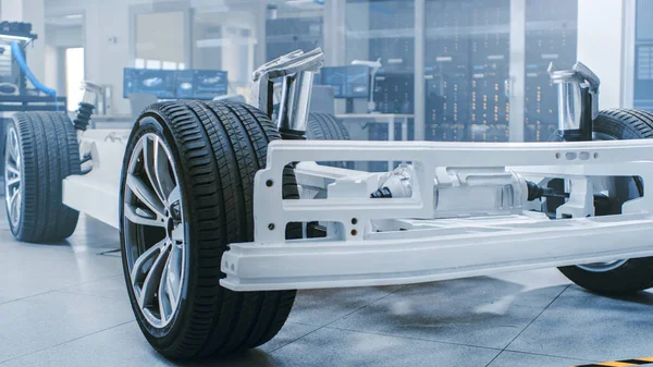 Concept van authentieke elektrische auto platform chassis prototype staande in high tech industriële machinebouw laboratorium. Hybride frame inclusief banden, ophanging, motor en batterij. — Stockfoto