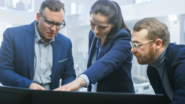 Ingenieure für Automobildesign arbeiten und diskutieren auf einem Computerbildschirm neben einem Prototyp für das Fahrwerk eines Elektroautos. im High-Tech-Labor mit Fahrzeugrahmen. — Stockfoto