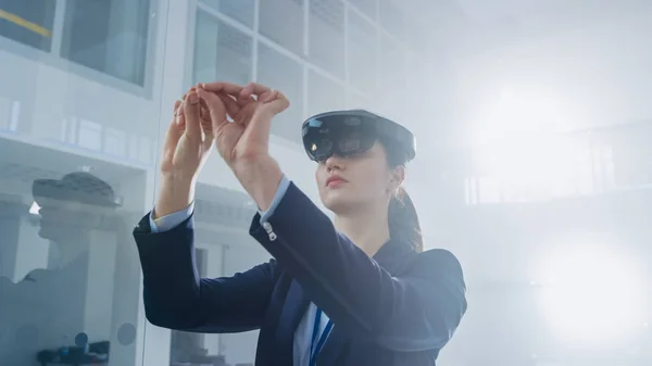Ingeniera femenina usando auriculares de realidad aumentada Haciendo gestos de trabajar con objetos virtuales en el aire. En innovación Laboratorio de alta tecnología con atmósfera futurista . —  Fotos de Stock
