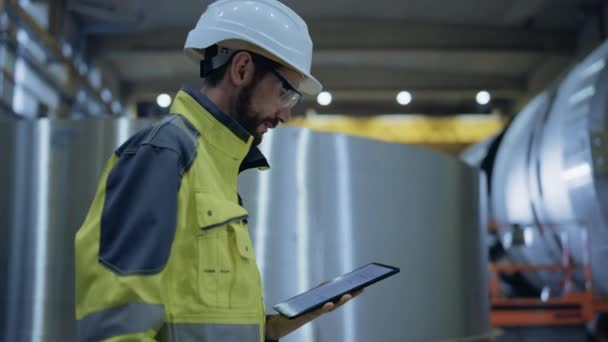 Ingénieur de l'industrie lourde marcher à travers l'usine de fabrication de tuyaux, Utilisez un ordinateur tablette numérique. Installation de construction de pipelines de pétrole, de gaz et de carburant Produits de transport. Vue latérale Mouvement lent 